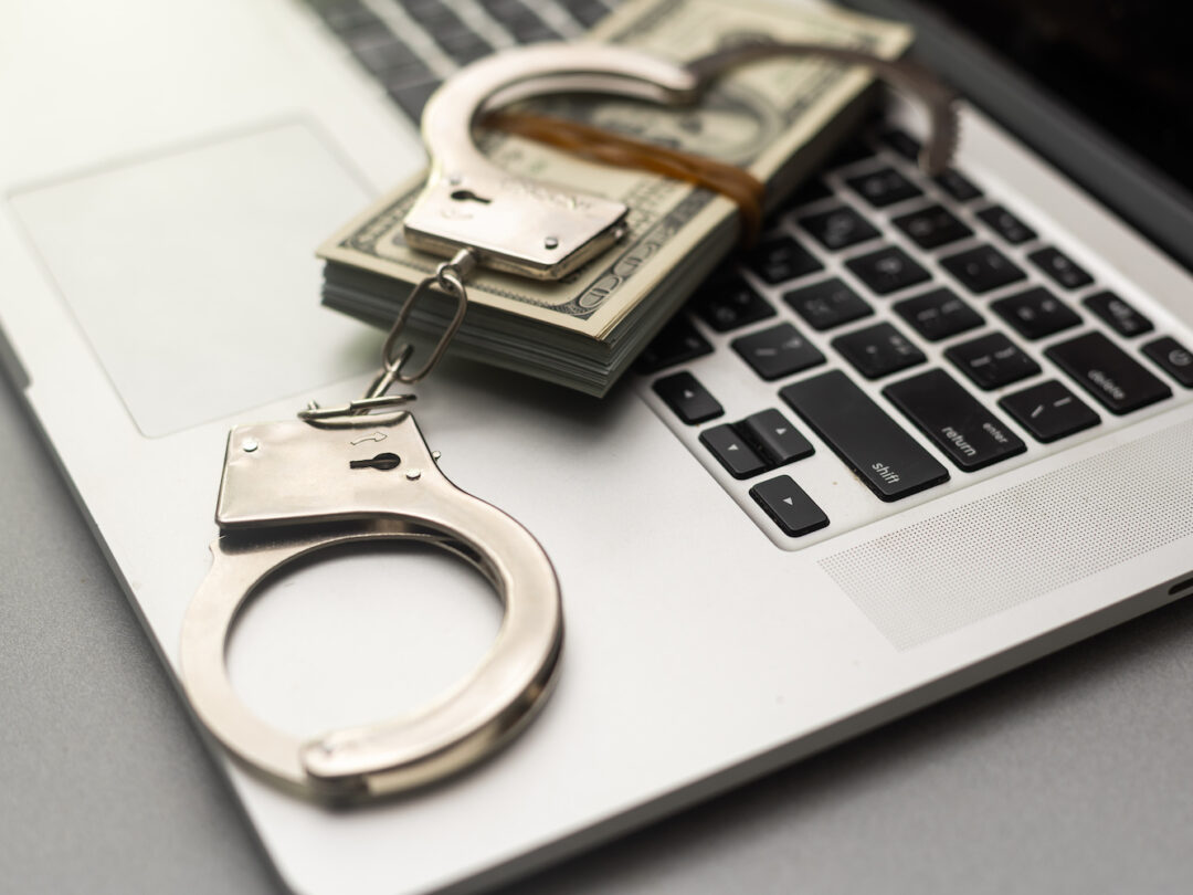 Handcuffs keyboard and dollars above.